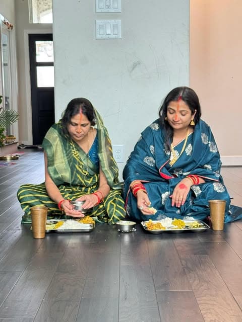 Two vratis seated on the floor observing Kharna