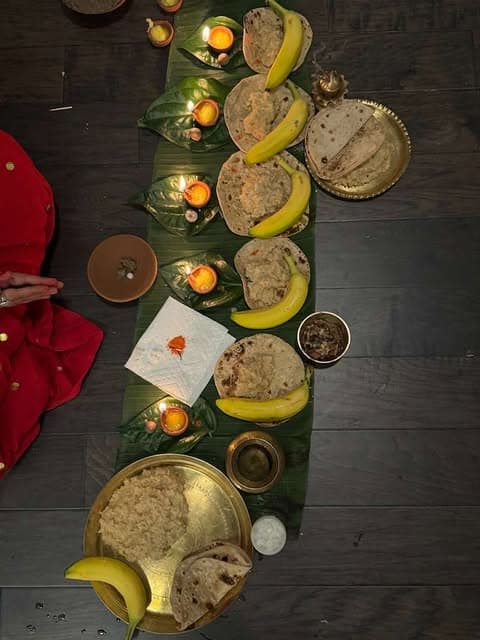 Prasad laid out on banana leaves with diyas, fruit and brass vessels