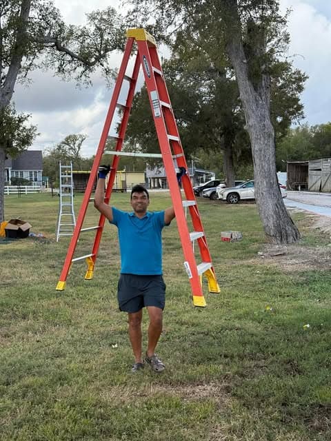 A volunteer carrying a ladder during site setup